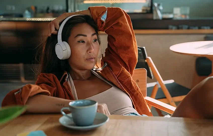 Woman wearing on-ear headphones comfortably at a café